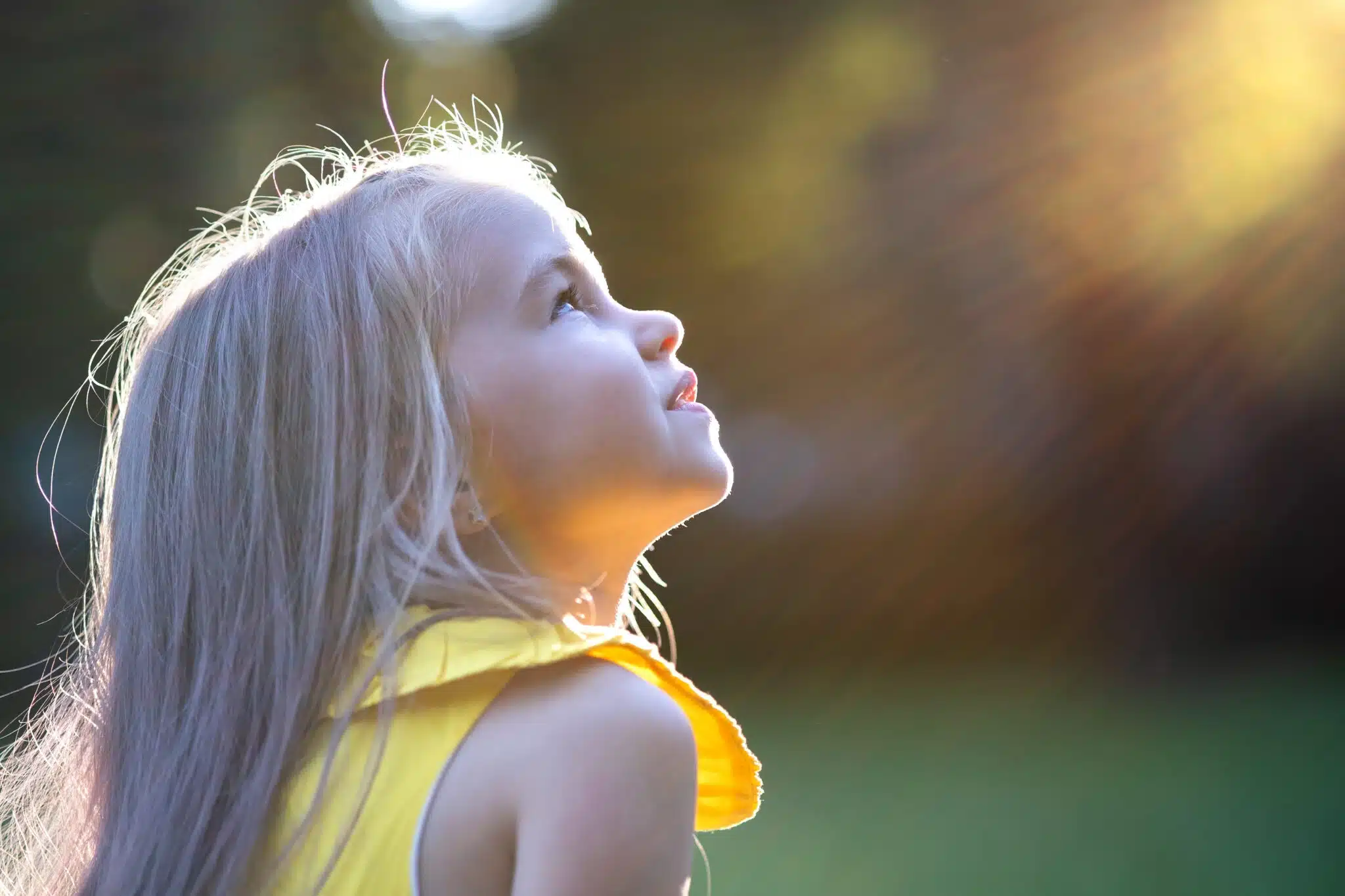 Young girl looking up at sunlight outdoors