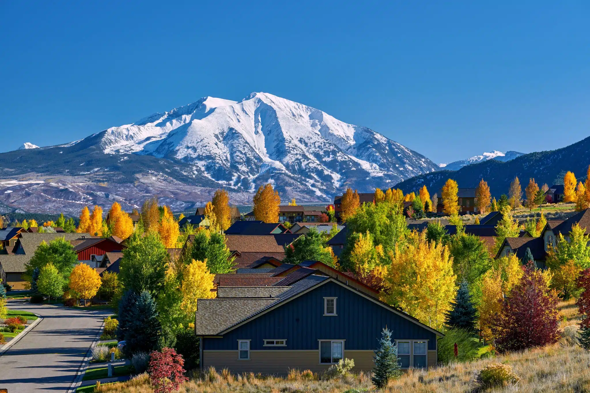Snow-capped mountain behind colorful autumn neighborhood