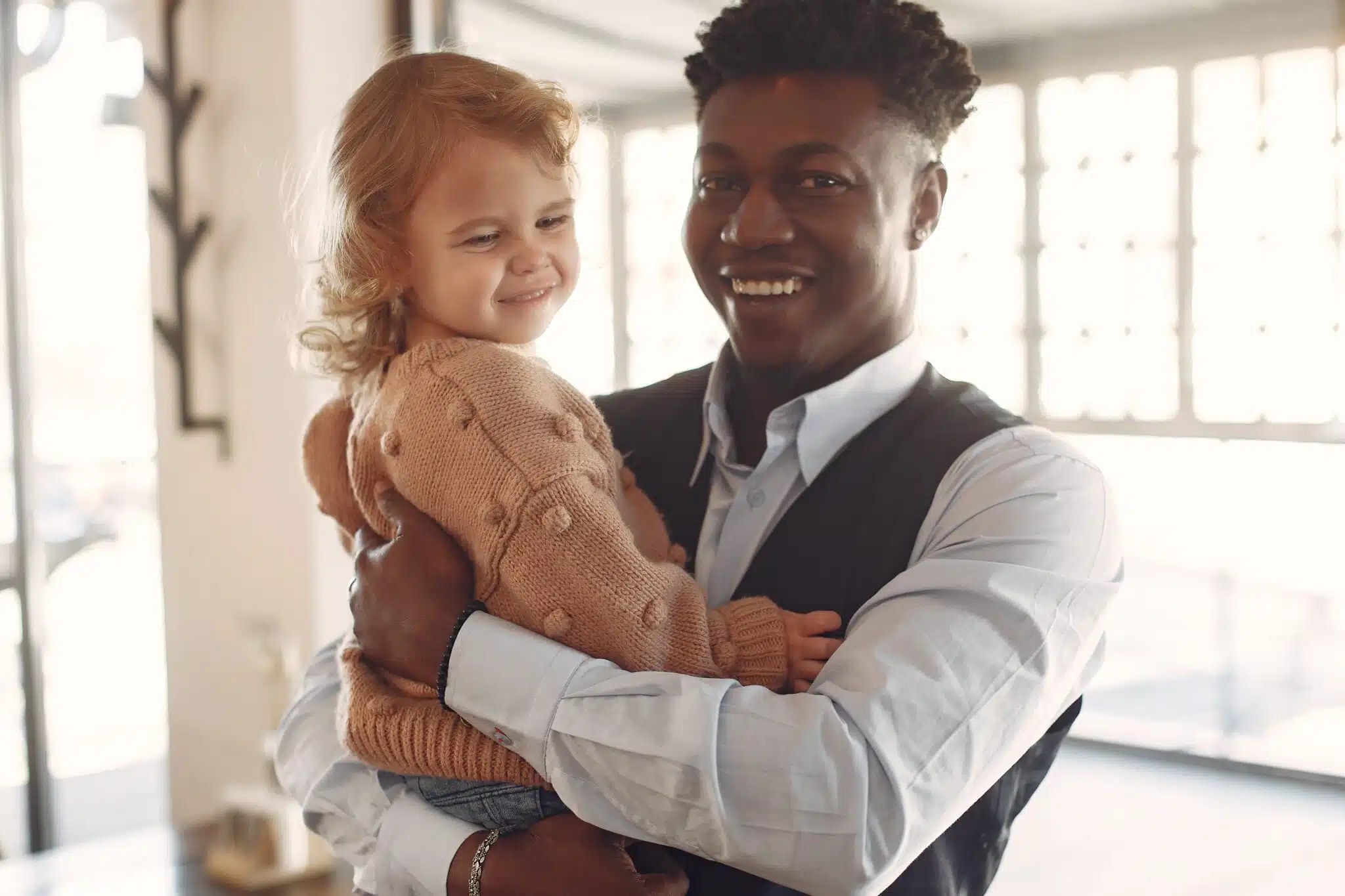Smiling man holding young child indoors
