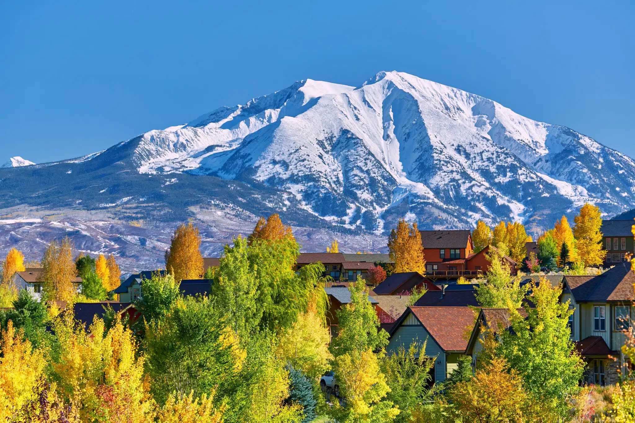Snow-capped mountain above colorful autumn neighborhood