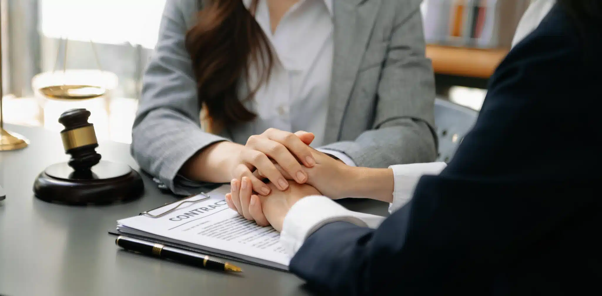 Client and lawyer holding hands over contract