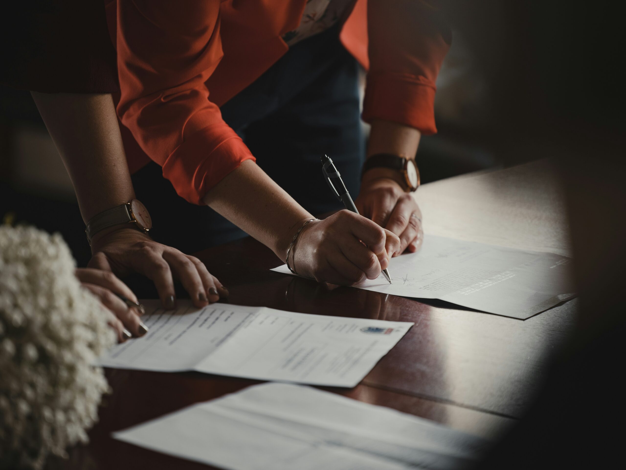 People signing documents at a table during a meeting