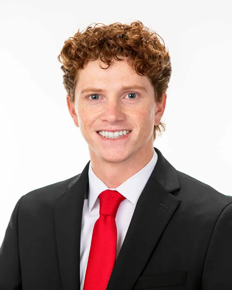Young man in suit with red tie smiling