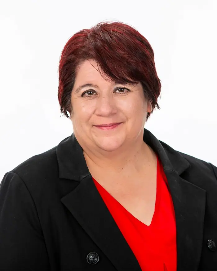 Professional headshot of woman in black blazer and red blouse