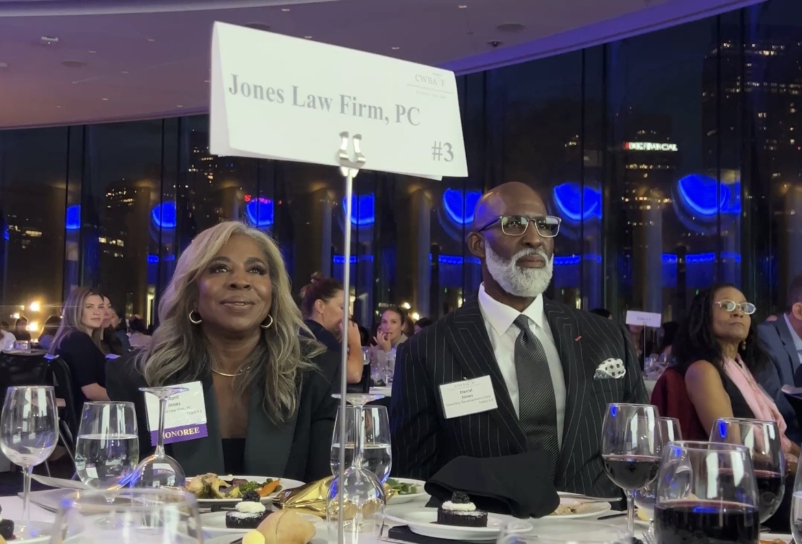 Honorees seated beneath Jones Law Firm table sign