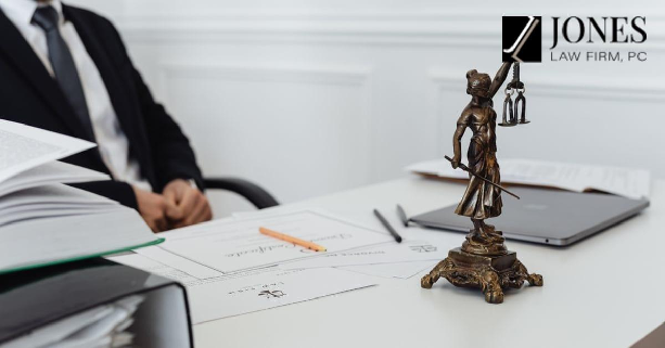 A legal professional's workspace featuring Lady Justice statue, documents, and a laptop, illustrating child support lawyer in Centennial. Branded with the Jones Law Firm PC logo.